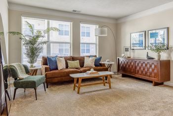 A living room with a brown couch, a green chair, and a wooden coffee table.